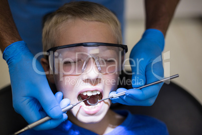 Dentist examining a young patient with tools