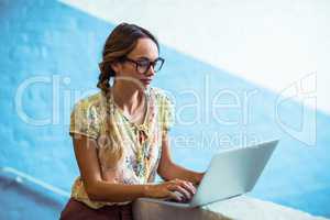 Woman standing near staircase and using laptop