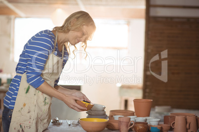 Female potter pouring watercolor in bowl