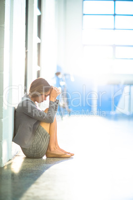 Tired businesswoman sitting on office corridor