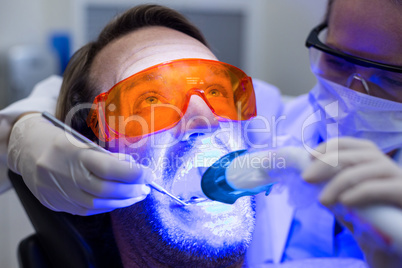 Female dentist examining male patient with tools