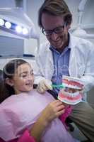 Dentist showing young patient how to brush teeth