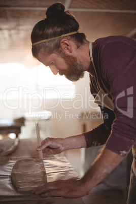 Male potter designing clay with sticks