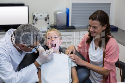 Dentist examining young patient with dental tool