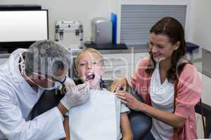 Dentist examining young patient with dental tool