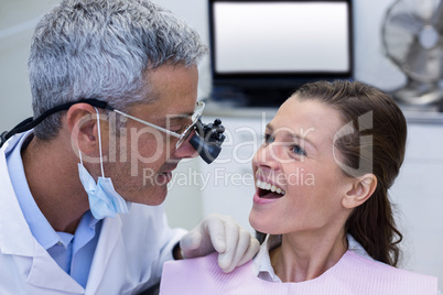 Dentist examining a female patient with dental loupes