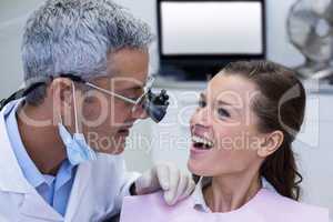 Dentist examining a female patient with dental loupes