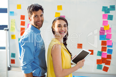Business executive and co-worker smiling and holding digital tab