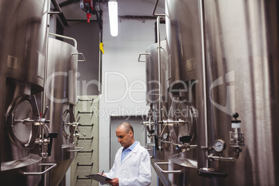 Manufacturer standing amidst storage tanks at brewery