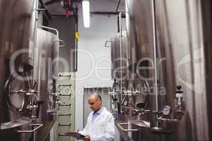 Manufacturer standing amidst storage tanks at brewery