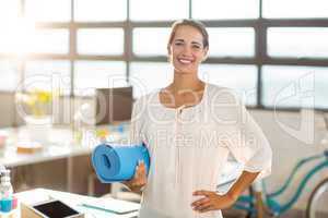 Female business executive holding exercise mat