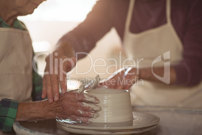 Mid-section of male potter assisting female potter
