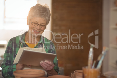 Female potter using digital tablet