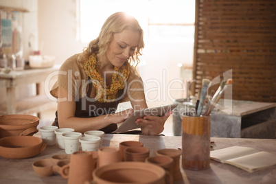 Beautiful female potter using digital tablet