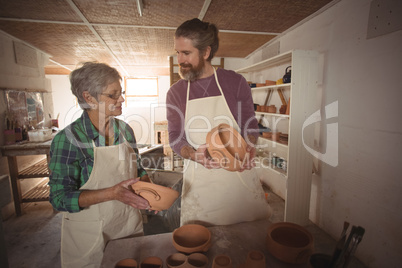 Male and female potter examining a pot