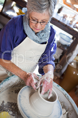 Attentive female potter making pot