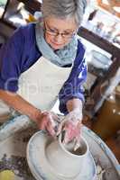 Attentive female potter making pot