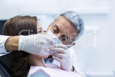 Dentist examining a female patient with tools