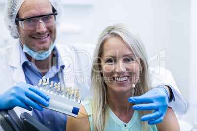 Dentist holding teeth shades while female patient smiling