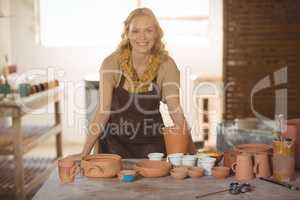 Beautiful female potter leaning on worktop