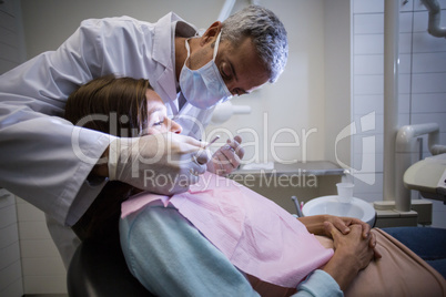 Dentist examining a female patient with tools