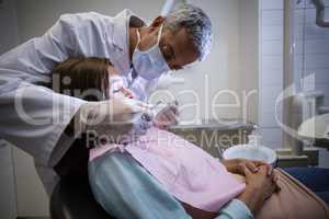 Dentist examining a female patient with tools