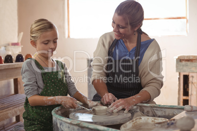 Happy female potter assisting girl