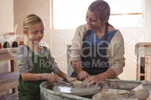 Happy female potter assisting girl