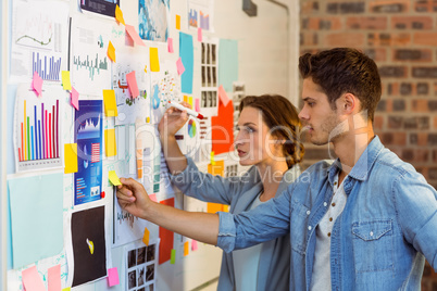 Business executives putting sticky notes on whiteboard