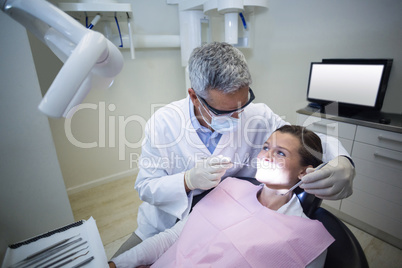 Dentist examining a young patient with tools