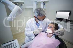 Dentist examining a young patient with tools