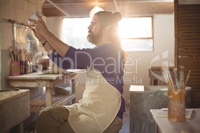 Male potter checking bowl