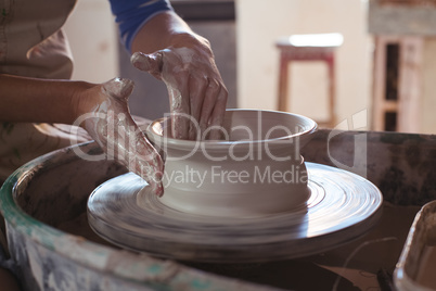 Mid section of female potter making pot