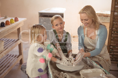 Smiling female potter assisting girls