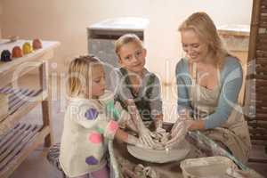 Smiling female potter assisting girls