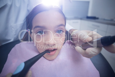 Dentist examining a young patient with tools