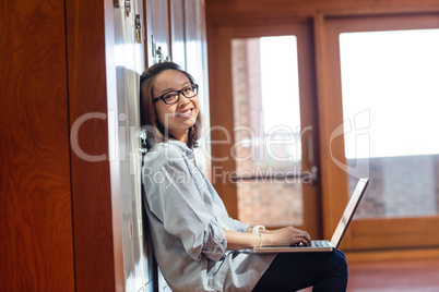 Happy young woman using laptop in locker room