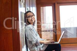 Happy young woman using laptop in locker room
