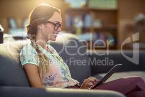 Business executive sitting on sofa and using digital tablet in o