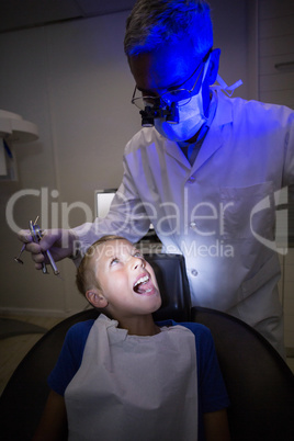 Dentist examining a young patient with tools