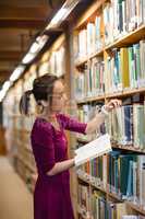 Young woman selecting book in library