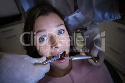 Dentist examining a female patient with tools