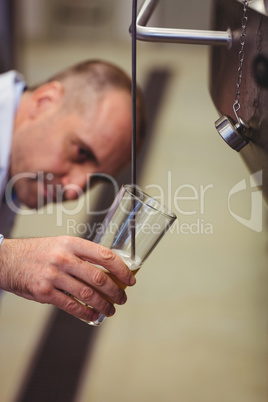 Manufacturer filling beer from storage tank at brewery