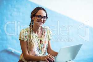 Woman standing near staircase and using laptop in office