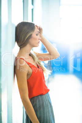 Tired businesswoman leaning on wall