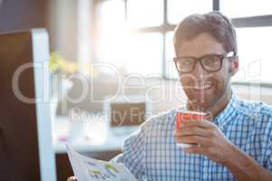 Male business executive holding newspaper while having coffee