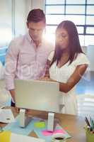 Business people discussing over laptop