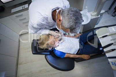 Dentist examining a young patient with tools