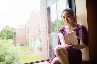 Young woman reading book in college