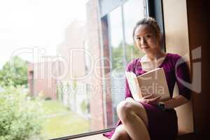 Young woman reading book in college